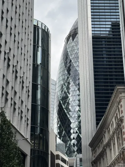A curved glass tower framed by neighbouring buildings on a London street