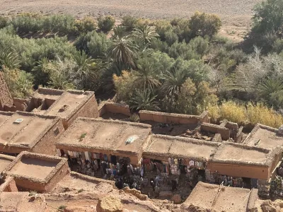 Earthen rooftops and market stalls beside palm trees at Ait Ben Haddou, Morocco