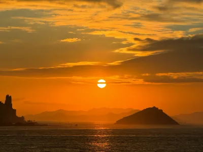Golden sunset over the water and distant hills, photographed outside the Hong Kong Palace Museum