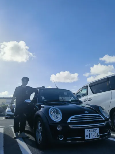 A travel photograph beside a black Mini Cooper in Okinawa