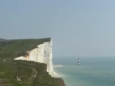 White chalk cliffs above the sea, with a lighthouse standing offshore
